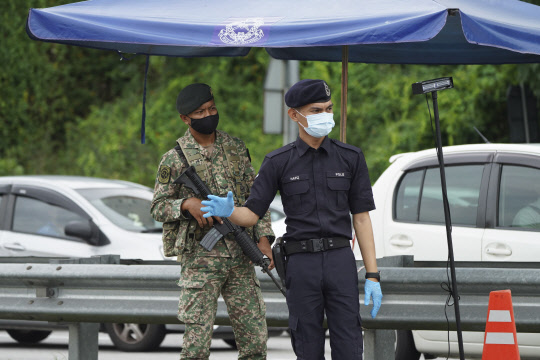 지난 11일(현지시간) 말레이시아 쿠알라룸푸르 외곽 도로에 설치된 검문소에서 경찰이 차량을 검문하고 있다. 무히딘 야신 말레이시아 총리는 코로나19 확산세가 이어지자 12일부터 다음 달 7일까지 3차 전국 이동통제령을 발령했다. <연합뉴스>